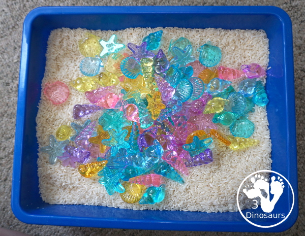 Shell and Rice Sensory Bin has a rice filler with acrylic sheets in different colors as the part in the sensory bin. This is a simple beach sensory bin idea for kids. - 3Dinosaurs.com