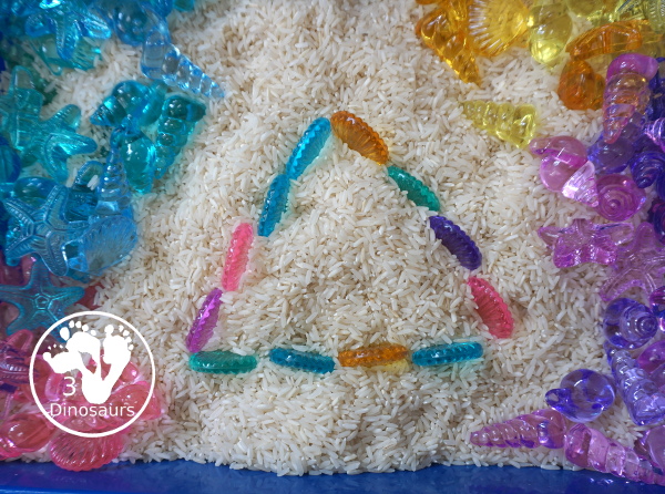 Shell and Rice Sensory Bin has a rice filler with acrylic sheets in different colors as the part in the sensory bin. This is a simple beach sensory bin idea for kids. - 3Dinosaurs.com