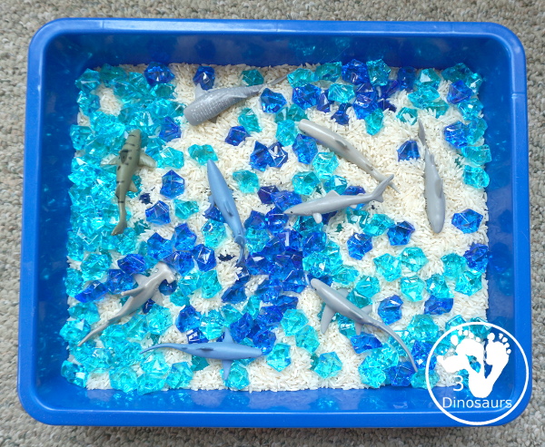 Shark Rice Sensory Bin for shark week with a mix of acrylic rocks, rice and a shark toob for the shark figures for kids to play in prek and kindergarten - 3Dinosaurs.com