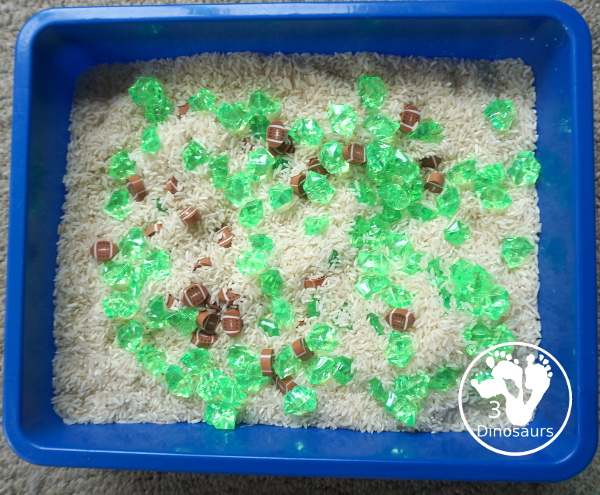 Football Sensory Bin - a simple football sensory bin for kids. You have a mix of green rocks, rice and footballs - 3Dinosaurs.com