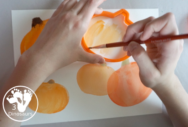 Pumpkin Cookie Cutter Watercolor Painting - a fun watercolor painting activity with pumpkin cookie cutters to make the pumpkins. Simple pumpkin paintings that different ages can do. - 3Dinosaurs.com