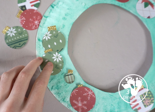 Christmas Wreath With Scrapbook Ornaments For Kids is a super easy Christmas wreath you can make with kids with a few simple items. - 3Dinosaurs.com