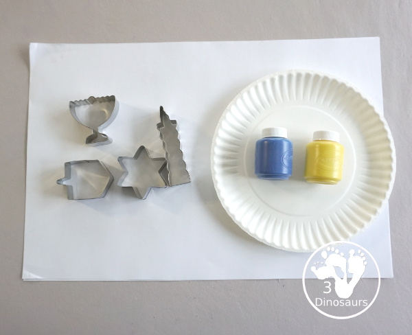  Hanukkah Stamping Painting with Cookie Cutters is a great Hanukkah craft you can do with different ages. And a fun mix of Hanukkah themes you can find in the cookie cutters.