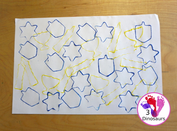  Hanukkah Stamping Painting with Cookie Cutters is a great Hanukkah craft you can do with different ages. And a fun mix of Hanukkah themes you can find in the cookie cutters.