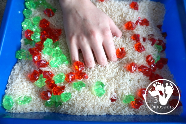 Christmas Red & Green Sensory Bin with red rocks and green rocks with a rice filler in a small bin that you can use for small sensory bin exploring with kids in preschool, preK and kindergarten. - 3Dinosaurs.com