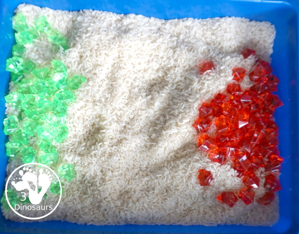 Christmas Red & Green Sensory Bin with red rocks and green rocks with a rice filler in a small bin that you can use for small sensory bin exploring with kids in preschool, preK and kindergarten. - 3Dinosaurs.com