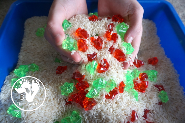 Christmas Red & Green Sensory Bin with red rocks and green rocks with a rice filler in a small bin that you can use for small sensory bin exploring with kids in preschool, preK and kindergarten. - 3Dinosaurs.com