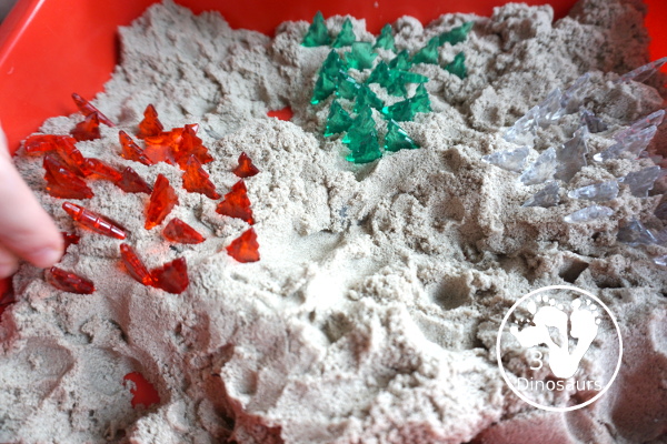 Christmas Tree & Kinetic Sand Sensory Bin - a simple sensory bin with a mix of red, green and clear evergreen trees in a kinetic sand fill for the sensory bin. This sensory bin is in a small paper bin that is great for sensory play with small groups. - 3Dinosaurs.com