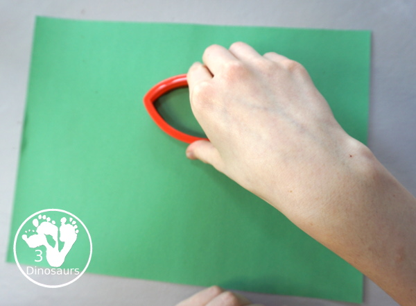 Football Stamp Painting with Cookie Cutters - You use a football shape cookie cutter to stamp brown footballs all over a green paper - 3Dinosaurs.com