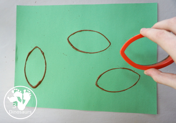 Football Stamp Painting with Cookie Cutters - You use a football shape cookie cutter to stamp brown footballs all over a green paper - 3Dinosaurs.com