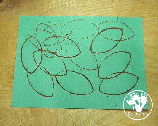 Football Stamp Painting with Cookie Cutters - You use a football shape cookie cutter to stamp brown footballs all over a green paper - 3Dinosaurs.com