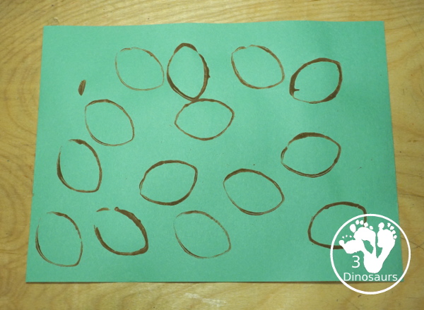 Football Stamp Painting with Cookie Cutters - You use a football shape cookie cutter to stamp brown footballs all over a green paper - 3Dinosaurs.com