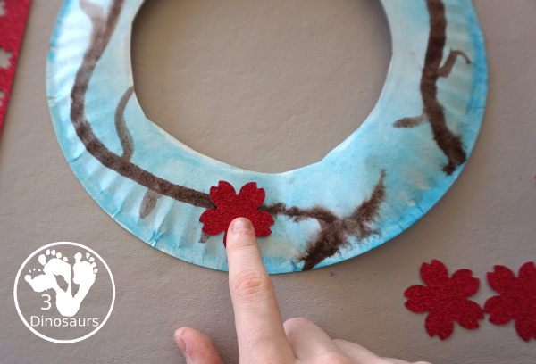 Cherry Blossom Wreath is a great spring wreath that kids can make with a paper plate for the base and watercolor and cherry blossom punches for the flowers. The Cherry Blossom Wreath is perfect for spring. - 3Dinosaurs.com