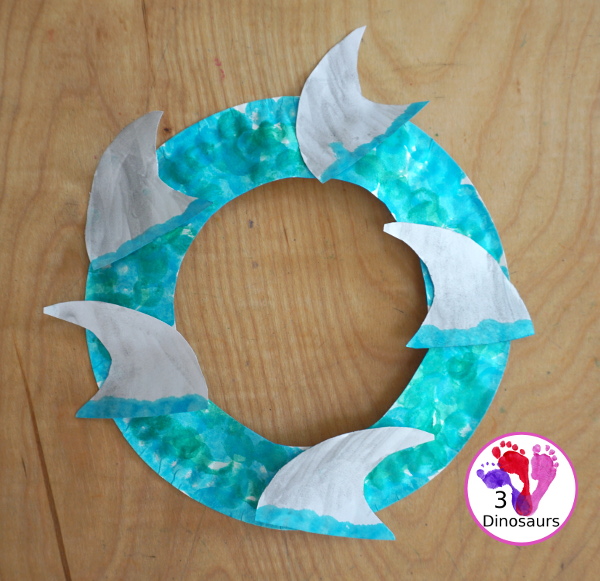 Shark Fin Wreath Craft for Shark Week - that kids can make with a shark cookie cutter and a paper plate. A super easy wreath for all ages.-  3Dinosaurs.com