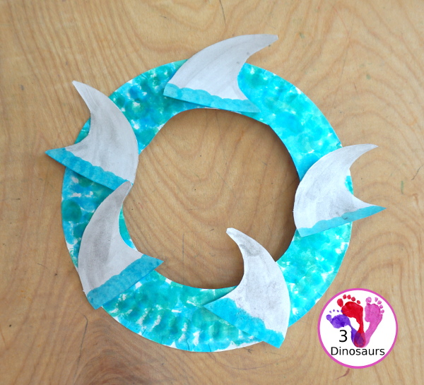 Shark Fin Wreath Craft for Shark Week - that kids can make with a shark cookie cutter and a paper plate. A super easy wreath for all ages.-  3Dinosaurs.com