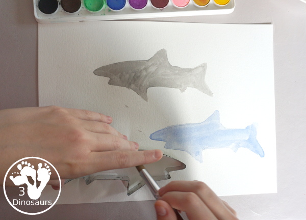 Shark Watercolor Painting with Cookie Cutters - a fun shark painting activity that you can do with kids for shark week. You use shark cookie cutter and watercolors - 3Dinosaurs.com