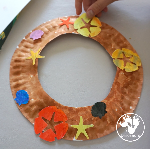 Beach Wreath Craft for Kids - a super easy to make beach craft with a wreath and shells kids can color and punch out to make the beach wreath. - 3Dinosaurs.com